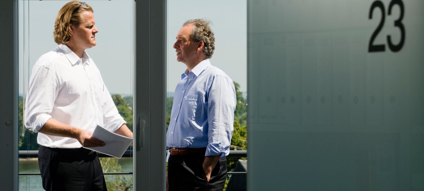 Herr Nacken und Herr Hillebrand stehen diskutierend auf dem Balkon des Bürogebäudes von Morison Köln.