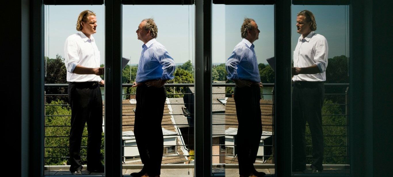 Herr Nacken und Herr Hillebrand stehen diskutierend auf dem Balkon des Bürogebäudes von Morison Köln.