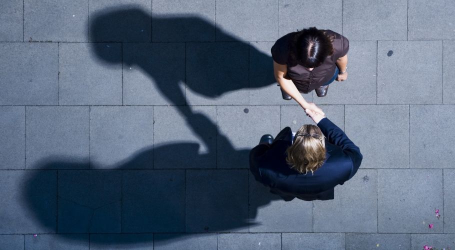 Man schaut von oben auf einen Mann und eine Frau, die sich die Hände schütteln.